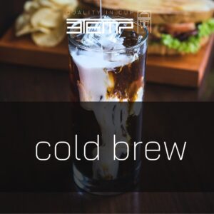 The image depicts a glass of cold brew coffee with ice, placed on a table, with a sandwich and chips in the background. There is text at the top that reads “QUALITY IN CUP,” and large text in the foreground reads “cold brew.”